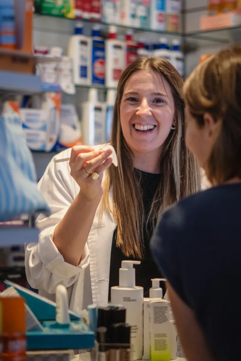 Pepa sonriendo en la farmacia mientras enseña un producto a una clienta